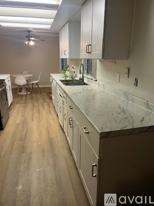 A kitchen with a marble countertop and wooden floors.