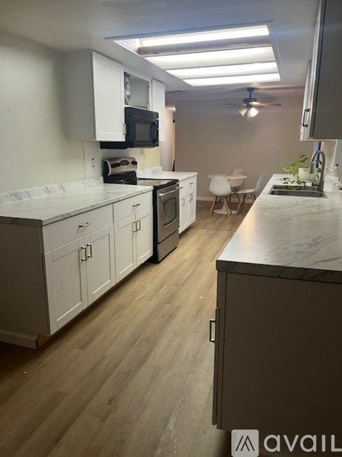 A kitchen with white cabinets and a wooden floor.