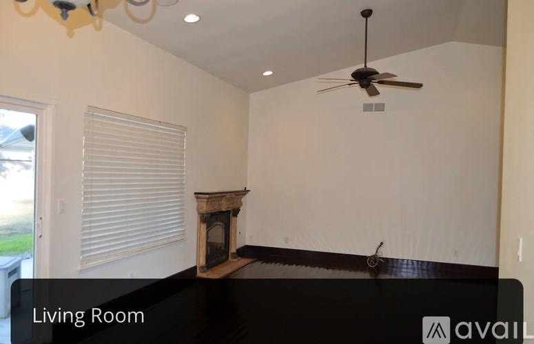 A living room with a fireplace and a ceiling fan.