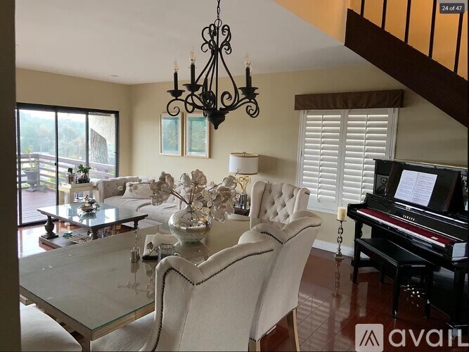 A living room with a piano and a glass table.