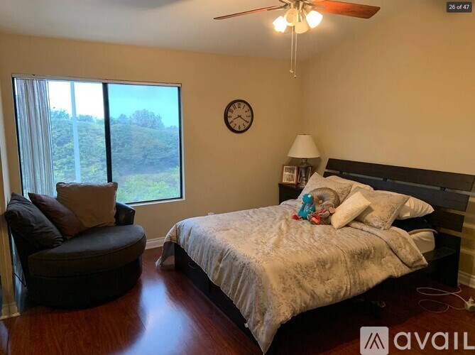 A bedroom with a bed, chair, and window.