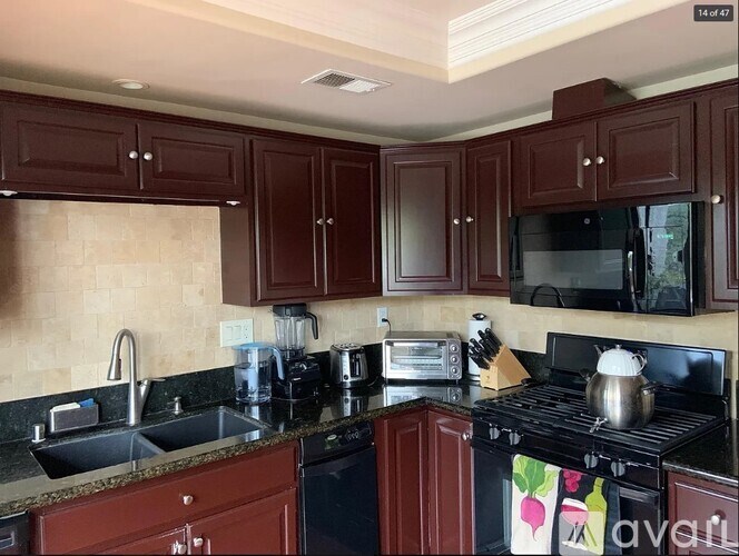 A kitchen with dark brown cabinets and black appliances.