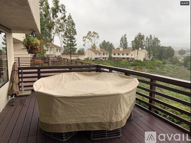 A hot tub on a deck with houses and trees in the background.