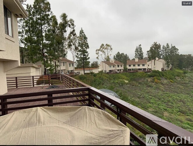 A balcony with a beige umbrella overlooking a row of houses.