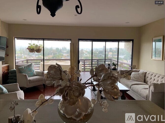A living room with a large window and a view of trees and buildings outside.