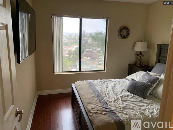 A bedroom with a large bed and a view of the city through the window.