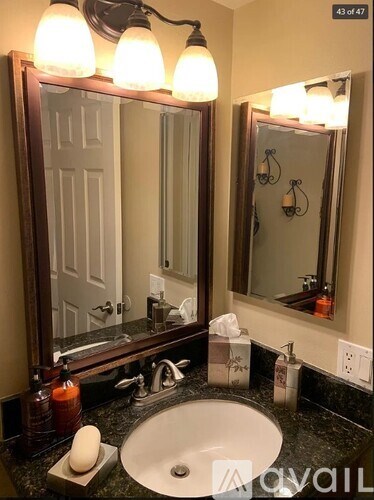 A bathroom with a sink, mirror, and lighting fixture.