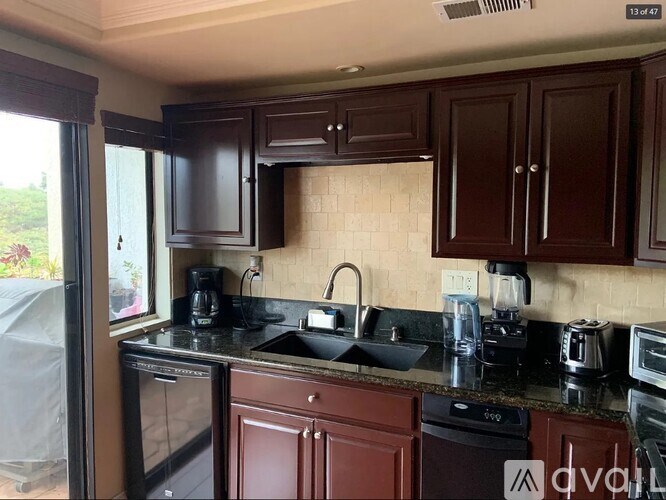 A kitchen with brown cabinets and black countertops.