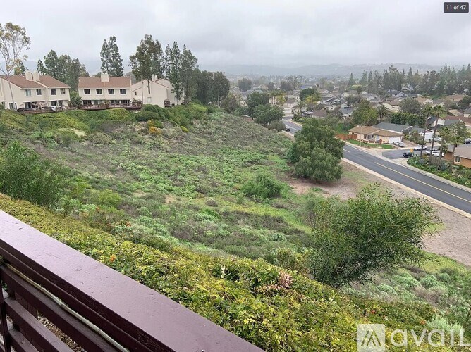 A view from a balcony overlooking a residential area with houses and a road.