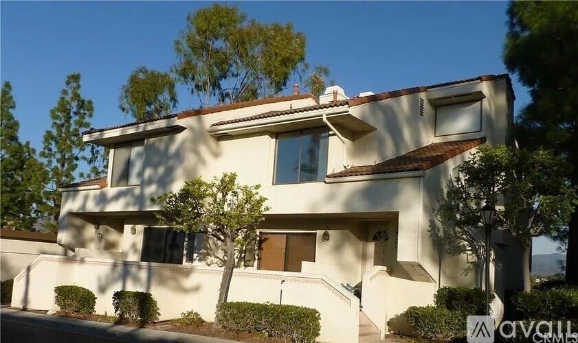 A modern house with a white exterior and a brown roof.