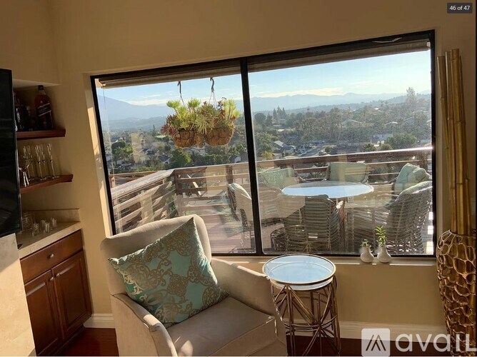 A living room with a chair and a table in front of a window with a view of the city.