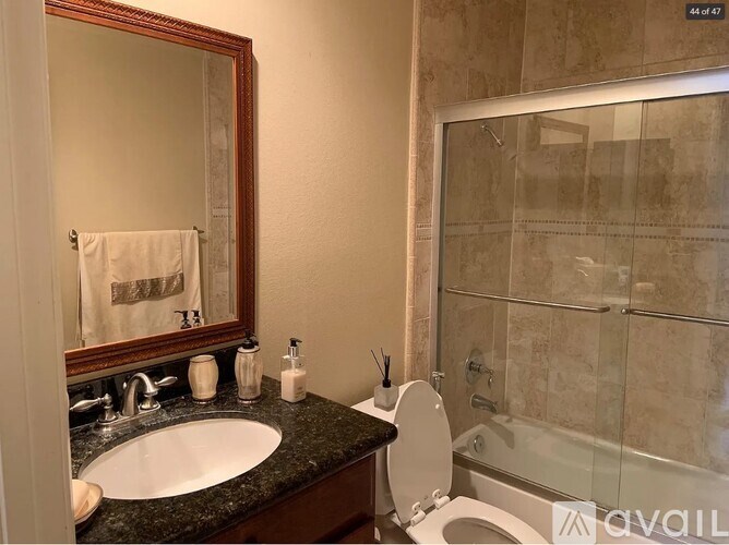 A bathroom with a sink, toilet, and a mirror.