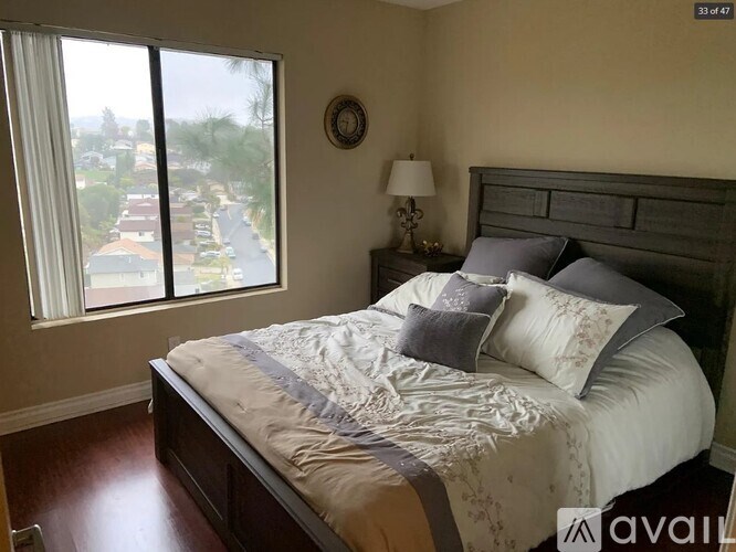 A bedroom with a large bed and a view of a street through the window.