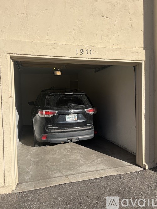 A black car is parked in a garage with the number 1911 on the wall.