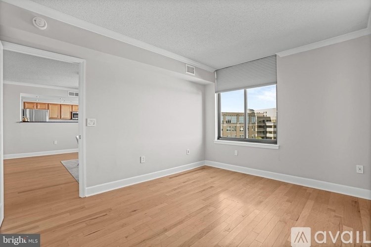 A spacious room with wooden flooring and a large window.