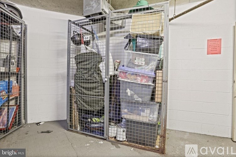 A person is standing inside a wire cage with various items inside.
