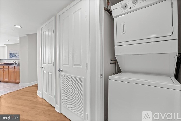 A white washing machine is in a kitchen with white cabinets.