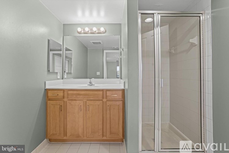A bathroom with a wooden vanity and a walk-in shower.