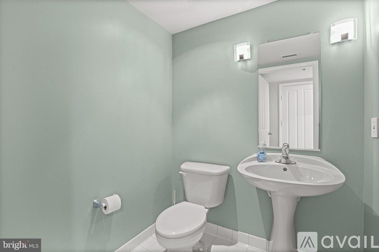 A bathroom with a toilet, sink, and mirror.