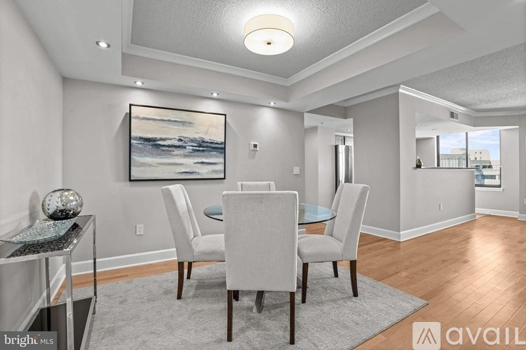 A dining room with a grey carpet and a painting on the wall.