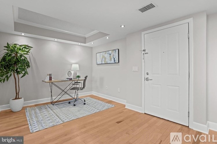 A room with a desk, chair, and a potted plant.