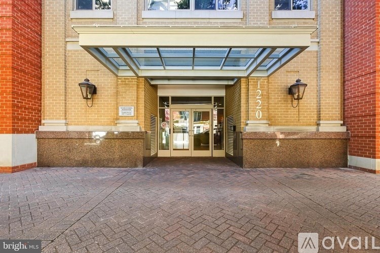 The entrance to a building with a glass roof and brick pillars.