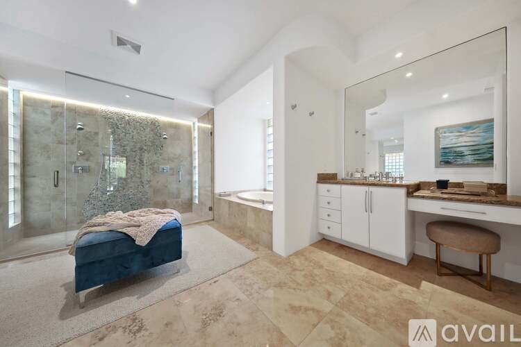 A modern bathroom with a glass shower and a blue bench.