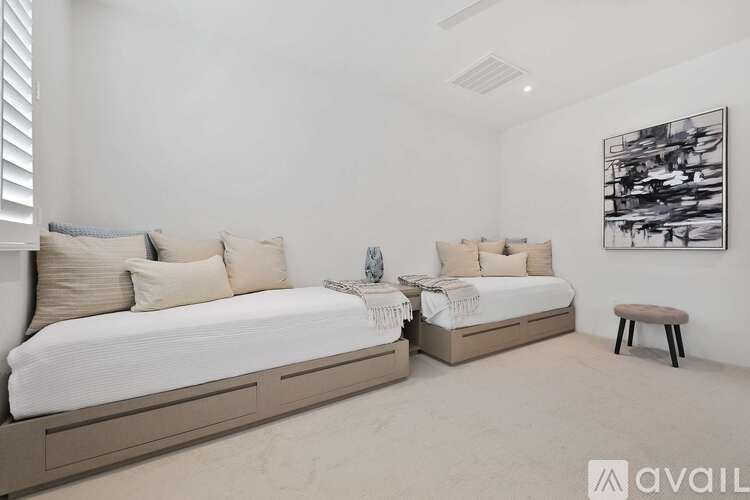 A bedroom with two beds and a bench.