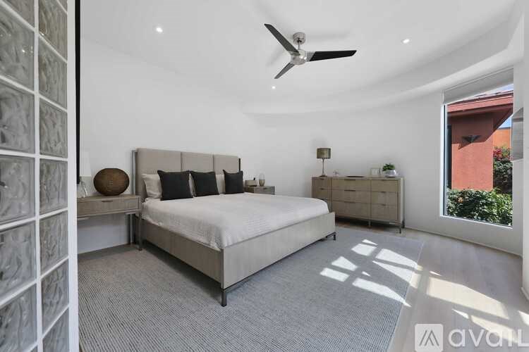 A bedroom with a large bed and a ceiling fan.