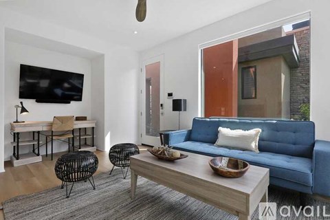 A living room with a blue couch, a wooden coffee table, and a television mounted on the wall.