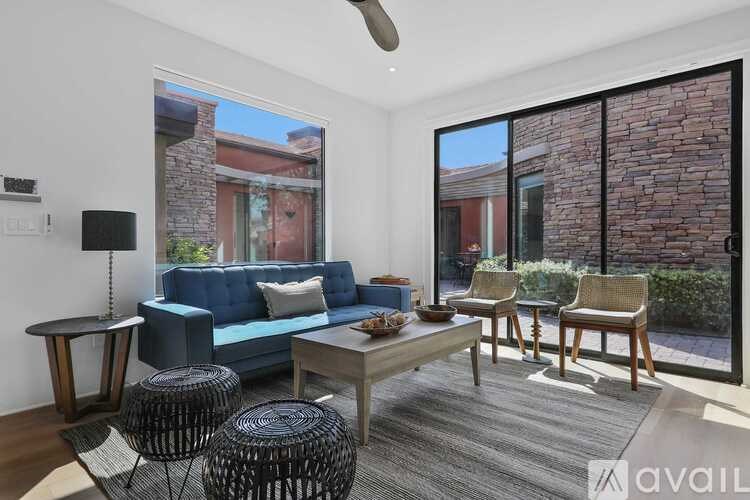 A living room with a blue couch, a coffee table, and a fan.