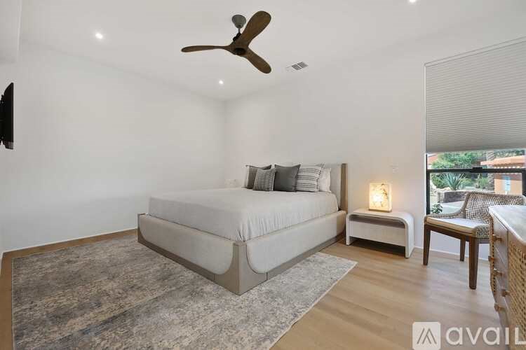 A bedroom with a bed, a chair, and a ceiling fan.