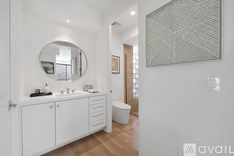 A bathroom with a round mirror and a white cabinet.