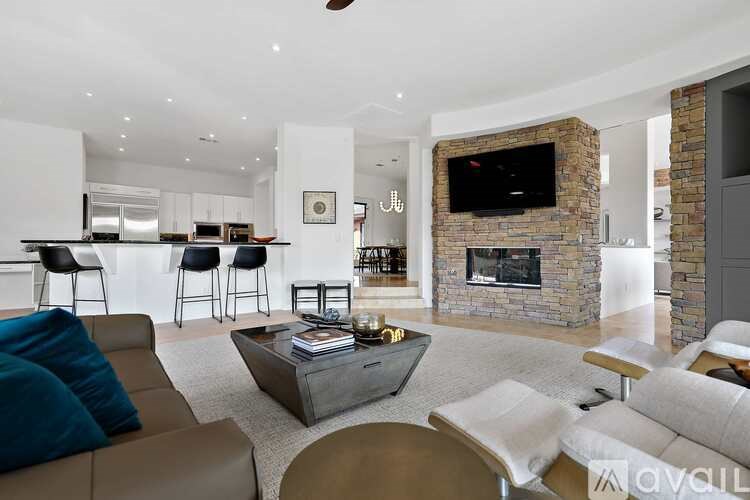 A modern living room with a stone fireplace and a flat screen TV mounted above it.