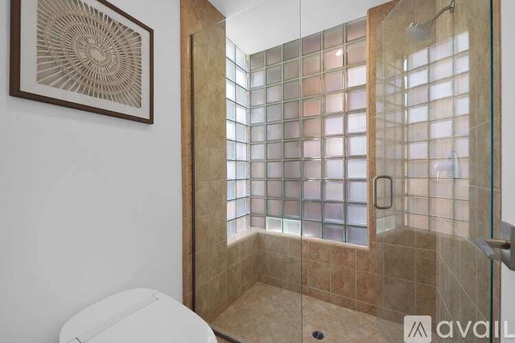 A bathroom with a glass shower door and a toilet.