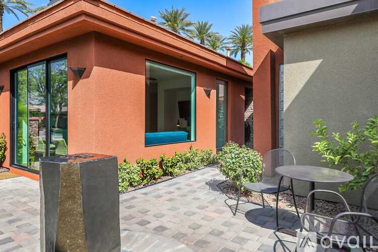 A patio with a table and chairs is in front of a house.