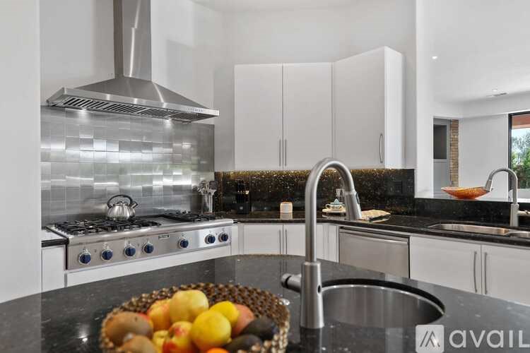 A modern kitchen with a stove, sink, and fruit bowl.