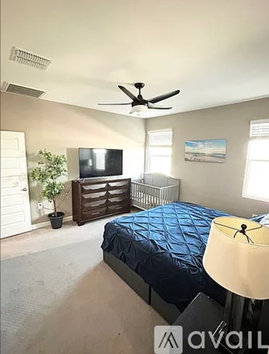A bedroom with a bed, dresser, and ceiling fan.