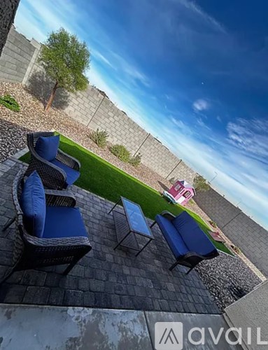 A patio with blue chairs and a table is set up on a stone floor.