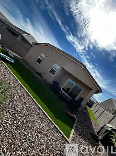 A house with a stone wall and a green lawn in front.
