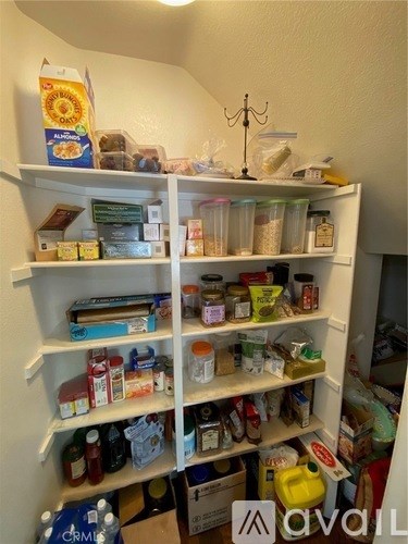 A white pantry with many food items on the shelves.