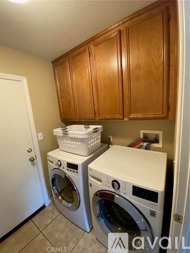 A white washing machine and dryer are stacked on top of each other in a small laundry room.