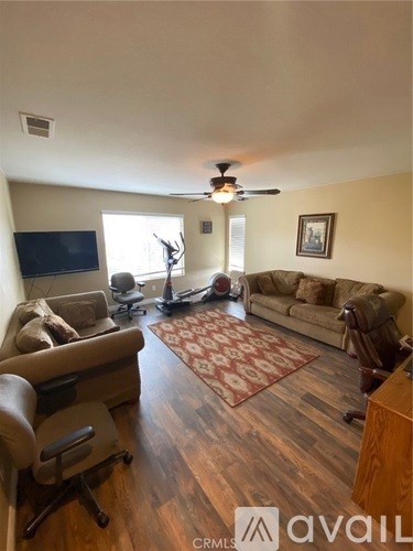 A living room with a brown couch, a chair, a television, and a rug.