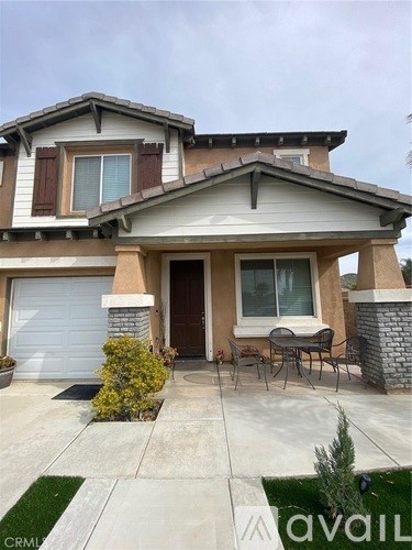 A house with a brown and white exterior and a patio with a table and chairs.