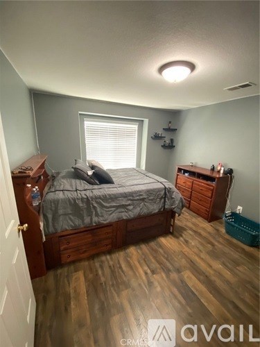 A bedroom with a bed, dresser, and window.