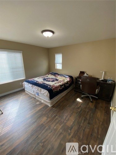 A bedroom with a bed, desk, and chair.