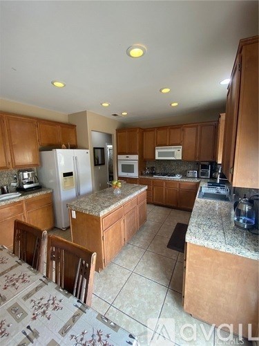 A kitchen with brown cabinets and a granite counter top.