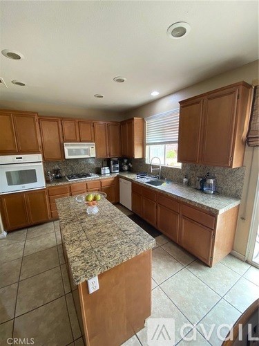 A kitchen with brown cabinets and granite countertops.