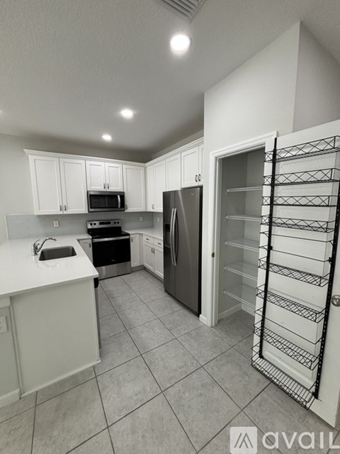 A kitchen with white cabinets and a black fridge.