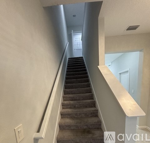 A staircase with a beige wall and a white railing.